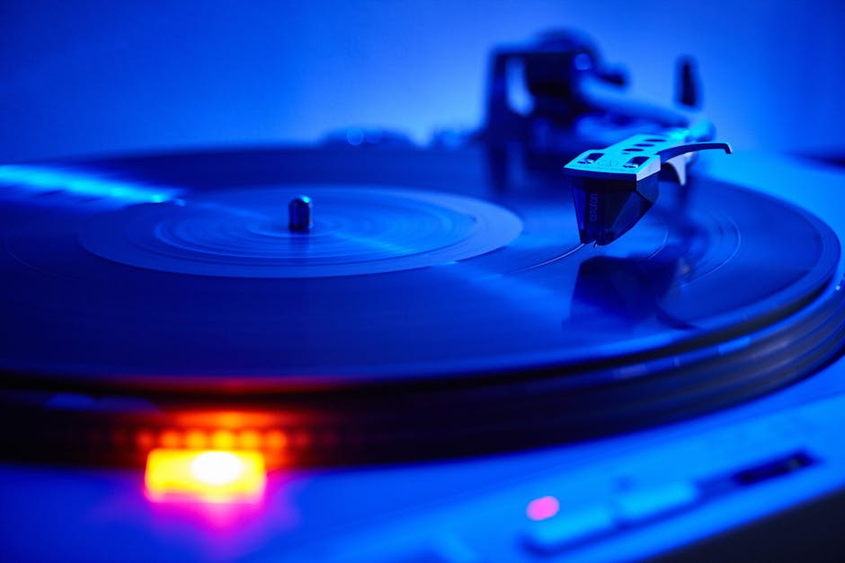 Vinyl record spinning on a turntable under cool blue light. Close-up view.